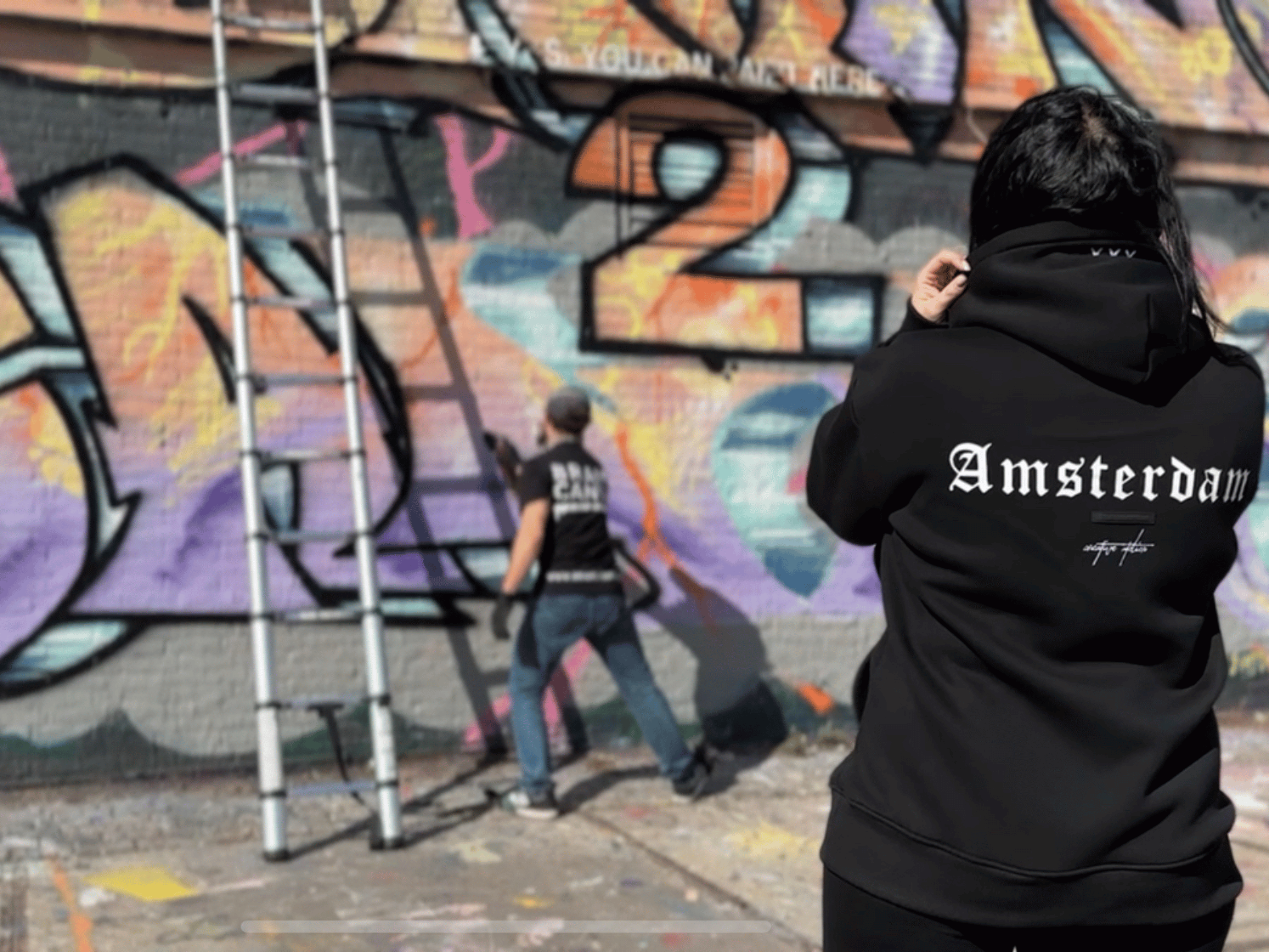 Team members working on a collaborative graffiti piece in an Amsterdam workshop